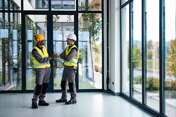 istock Two Construction Workers in High-Visibility Gear Discuss Project Inside Modern Glass-Walled Office Space 2249439108