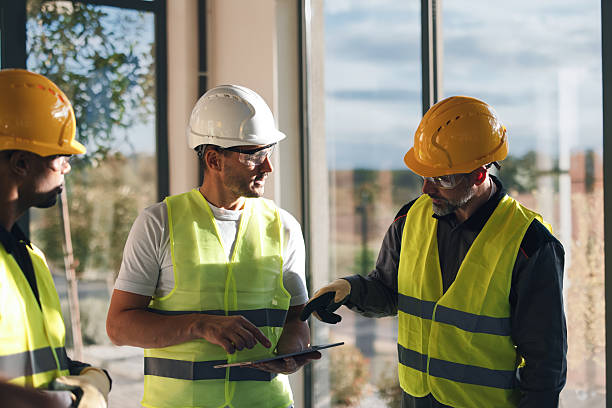istock Construction Team Discussing Plans Inside Modern Office Space, Safety Gear On Site 2249439136