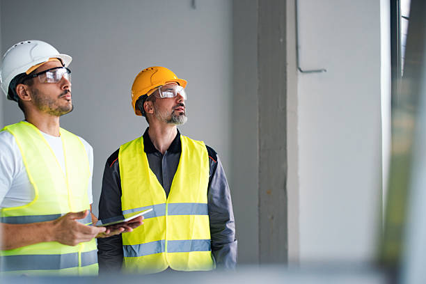 istock Construction Workers In High-Visibility Vests Inspecting Site, Planning New Office Space 2249439300
