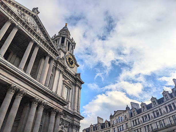 London, UK - November 08 2025: A low-angle perspective showing the majestic English Baroque facade and iconic clock tower of St. Paul's Cathedral reaching towards a dramatic, partly cloudy sky