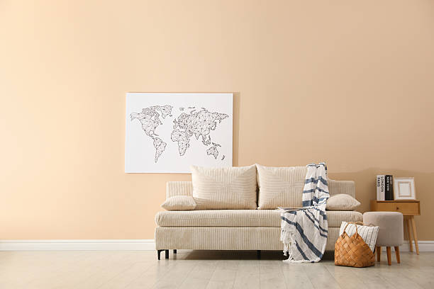 Comfortable sofa with pillows, blanket, pouf and picture indoors