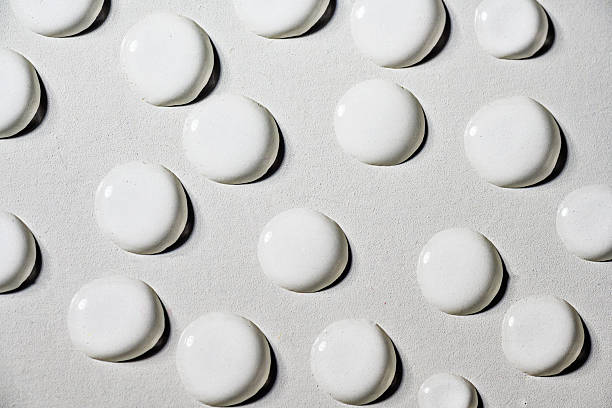 Closeup view of white fluid drops on a textured grey background