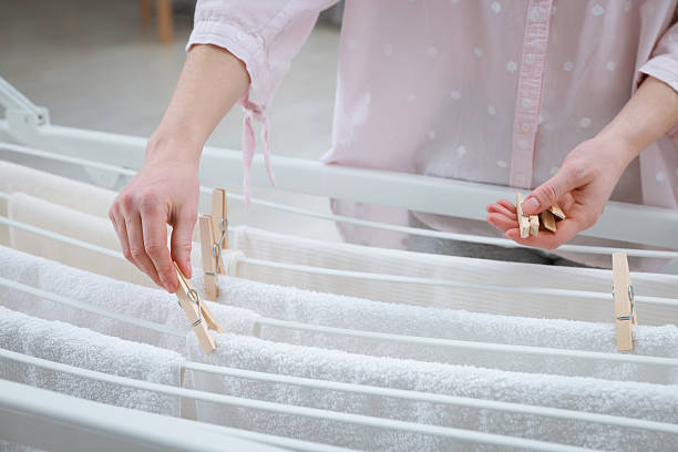 Woman hanging fresh clean laundry on drying rack at home, closeup