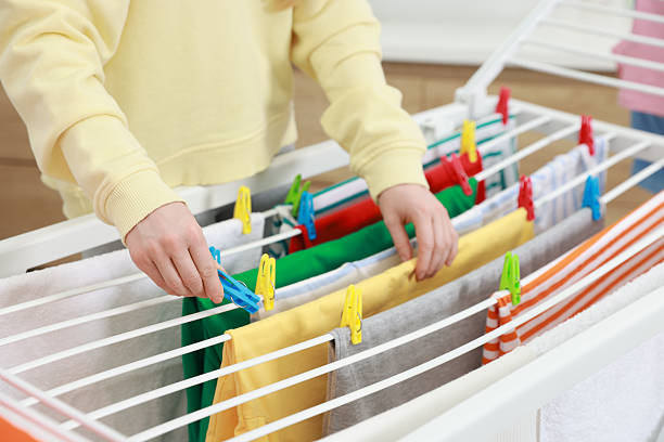 Woman hanging fresh clean laundry on drying rack at home, closeup