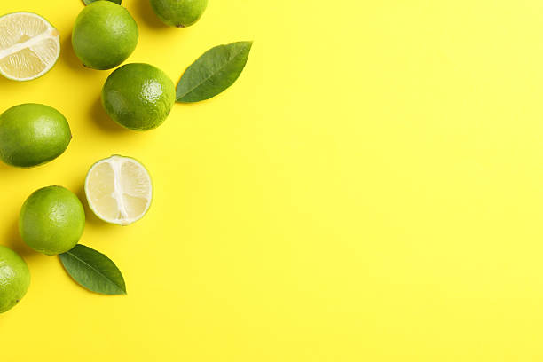 istock Fresh limes and leaves on yellow background. Space for text 2249450102