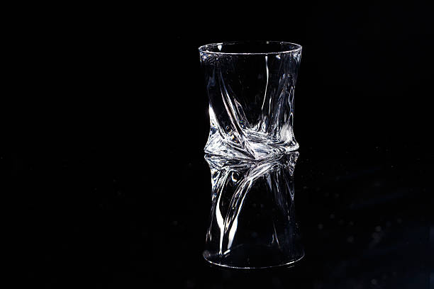 istock Black background stands a clean glass with reflection on a glass table. Facets on a Glass Cup 2249452142