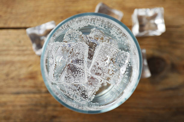istock Refreshing soda water with ice cubes in glass on wooden table, top view 2249455276
