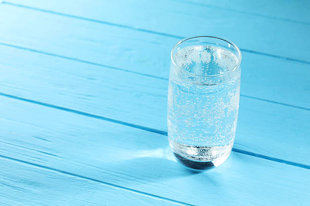 istock Refreshing soda water in glass on light blue wooden table, closeup. Space for text 2249455334