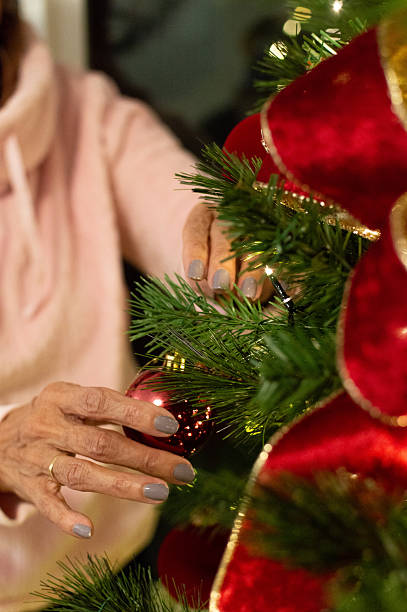 istock Hands Hanging Christmas Ornaments on Tree. 2249463116