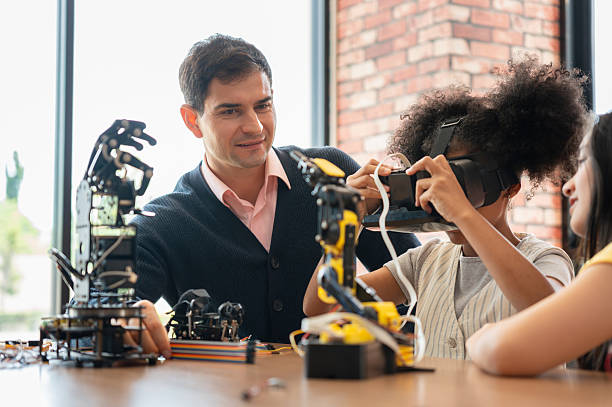 istock Teacher and Student Exploring Virtual Reality in a STEM Class, Young Girl Holding VR Headset While Learning Robotics and Technology, Technology in Education 2249465305