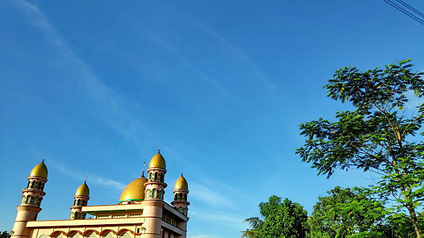 istock Mosque stands tall with golden domes under a clear blue sky, showcasing Islamic architecture 2249465769