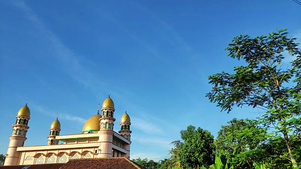 istock Mosque stands tall with golden domes under a clear blue sky, showcasing Islamic architecture 2249465930