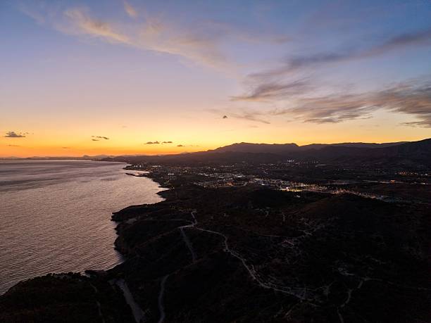 istock breathtaking aerial shot capturing sun setting over peaceful sea with rugged cliffs and distant town lights 2249470675