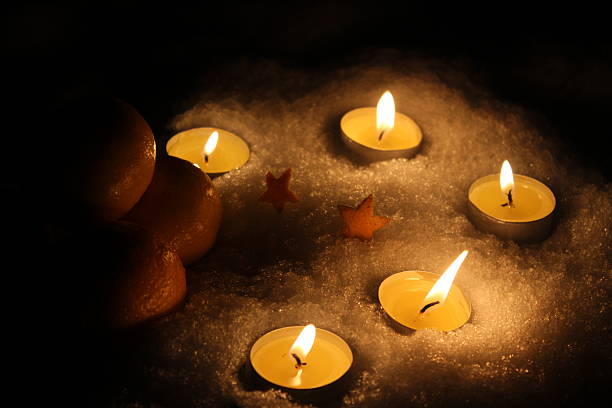 Candles and tangerines on snow create cozy winter evening atmosphere, filling the space with soft light, warmth and festive mood