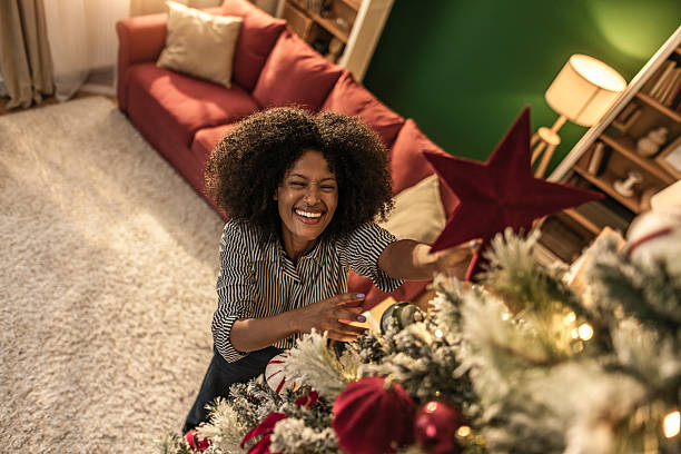istock Happy black woman decorating a Christmas tree at home on Christmas 2249480192