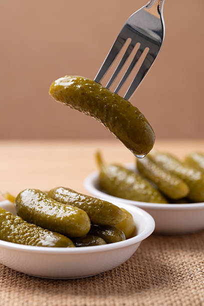 Pickled cucumber or Gherkin pickle in a bowl with fork