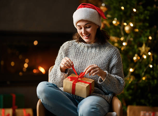 istock woman with present near Christmas tree indoors 2249490493