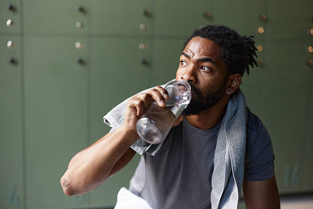 istock Black male athlete drinking water at gym's locker room. 2249491587