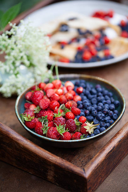 Different fresh ripe berries and mint on table outdoors, space for text