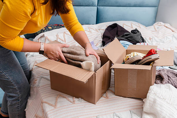istock A young woman sorting clothes and packing into cardboard boxes. Donations for charity, help low income families, declutter home, sell online, moving moving into new home or recycling 2249493848