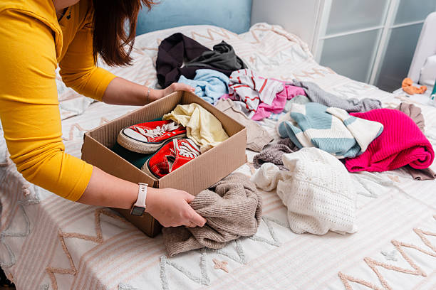 istock A young woman sorting clothes and packing into cardboard boxes. Donations for charity, help low income families, declutter home, sell online, moving moving into new home or recycling 2249493860