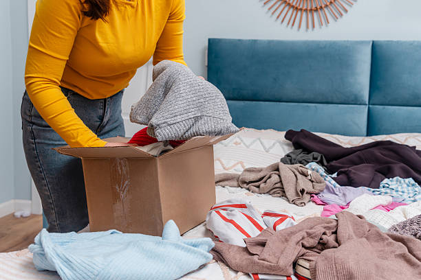istock A young woman sorting clothes and packing into cardboard boxes. Donations for charity, help low income families, declutter home, sell online, moving moving into new home or recycling 2249493947