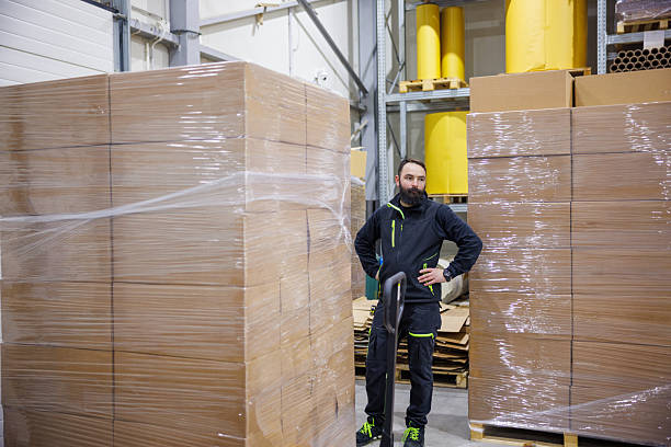 istock Man standing by the stack of goods in cardboard boxes in the distribution center 2249494838