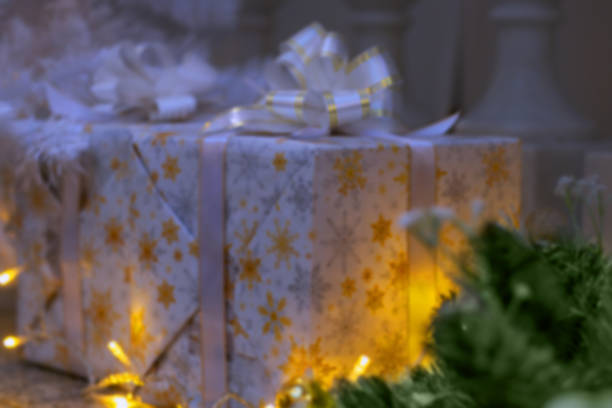 Christmas silvery gifts boxes with bow and lights creates warm and inviting holiday atmosphere. For background, backdrop.