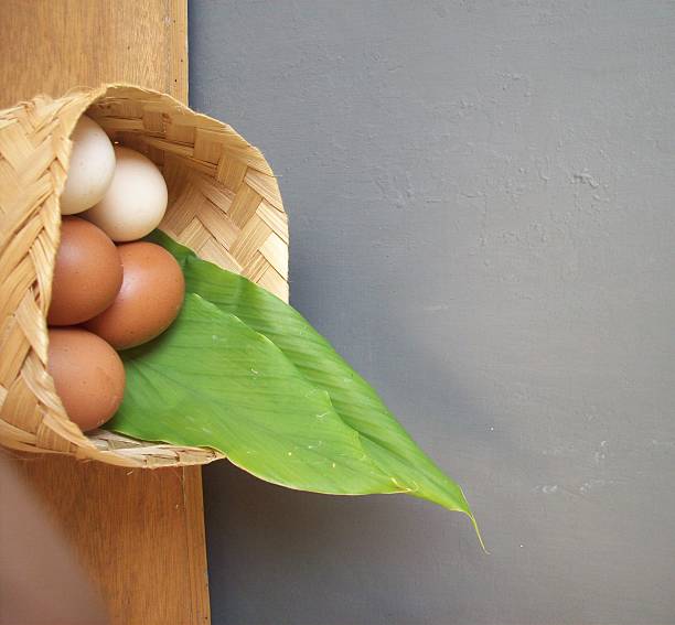 close up of several chicken and duck eggs in a woven bamboo container