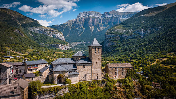 Aerial view of Torla and the historic Church of San Salvador in the Ordesa Valley of the Spanish Pyrenees. Monte Perdido massif in the background. Bright summer sky. Torla-Ordesa in Aragón, in the province of Huesca, northern Spain - Europe