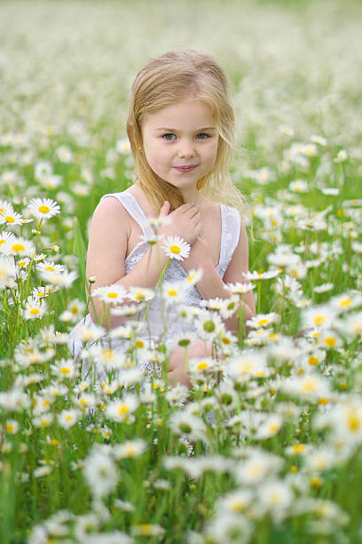 Cute little girl in big chamomile meadow. Portrait composition.