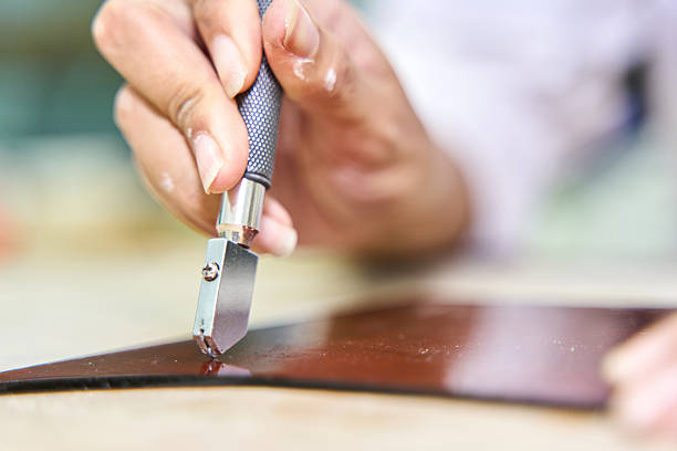 istock Artisan hand cutting glass with a glass cutter 2249503380