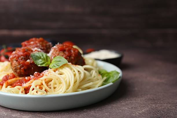 istock Delicious pasta with meatballs, basil and cheese on brown textured table, closeup. Space for text 2249505519