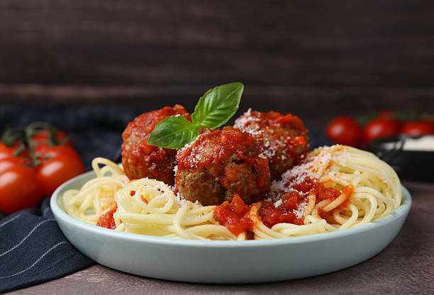 istock Delicious pasta with meatballs, basil and cheese on brown textured table, closeup 2249505647