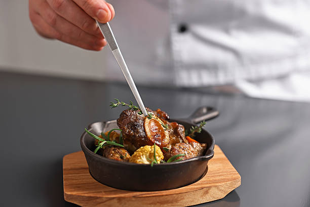 Professional chef serving dish at table indoors, closeup