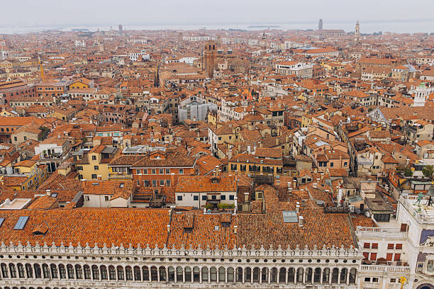 Venice cityscape from above, a sea of traditional terracotta rooftops covering historical buildings under a soft sky