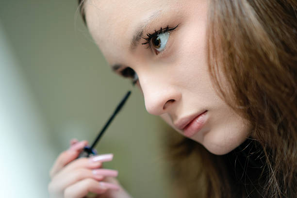 Close-up photo of a teenage girl applying mascara to enhance her eyelashes. Young, stylish girl showcasing self-care and beauty in her personal makeup routine.
