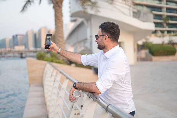istock Stylish man taking a selfie by the water in a modern setting. 2249511526