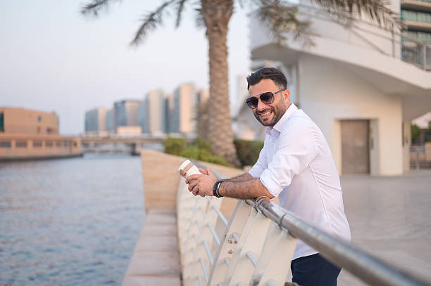 istock Man with sunglasses sipping coffee by the waterfront. 2249511564
