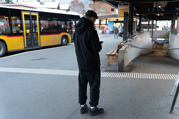 istock Man waiting at bus station using phone 2249511916