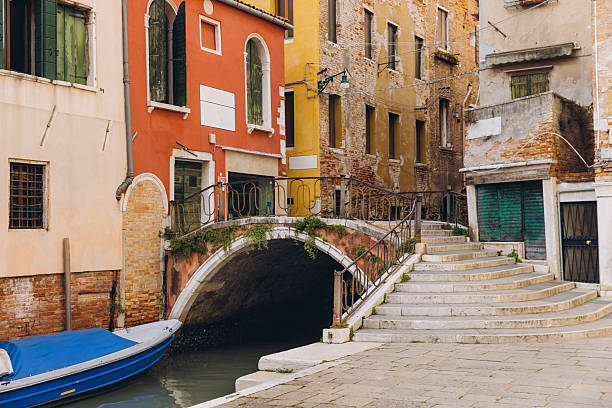 Historic waterway in Venice featuring an aged arch bridge, traditional buildings, a calm canal, and a small moored boat