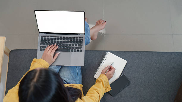 istock Lifestyle. Woman working on a laptop while taking notes in a cozy home environment. 2249513178