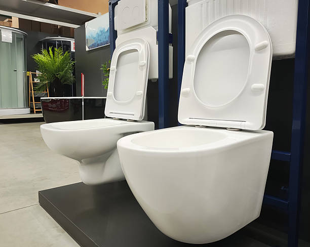 istock Two white ceramic wall hung toilets on display in a modern showroom with lids open, showcasing contemporary bathroom fixture design and space saving solutions 2249514787