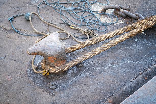 Close-up of heavy-duty ropes secured to a weathered mooring bollard on a concrete dock, used for securing ships and boats.