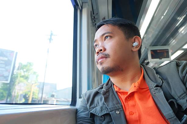 istock A Southeast Asian man sits by a bright train window, resting his chin on his hand while gazing outside, creating a reflective and peaceful travel moment. 2249521029