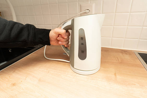 istock Person holding electric kettle on kitchen countertop 2249522639
