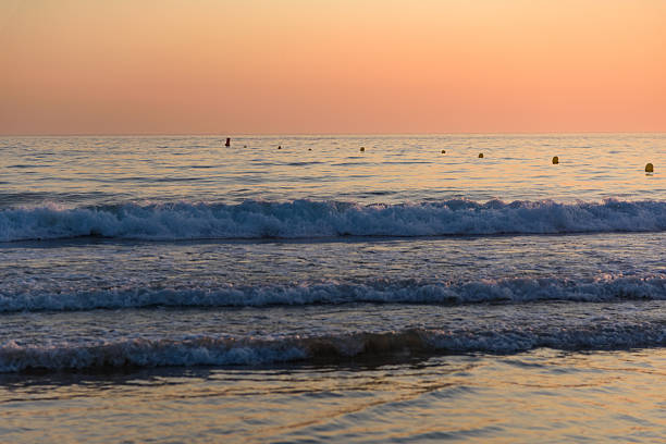 Idyllic scene with the shallows of the sea reflecting the sky and surf breaking in the distance.