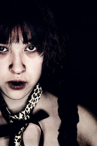 A close-up shot of a witch's face as she raises her long, sharp black nails toward her face. The intense stare and eerie lighting create a mysterious and spooky Halloween atmosphere