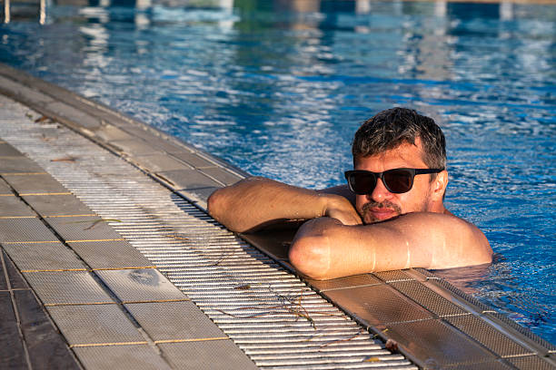 A man rests comfortably at a poolside in Naxos, Greece, capturing a carefree holiday atmosphere.