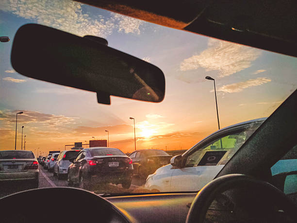 A view from inside a car of heavy traffic on a highway during a beautiful, vibrant sunset or sunrise.